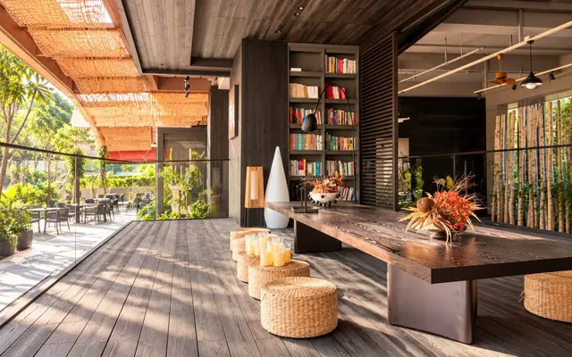 Open-air lounge with a long wooden table and woven seats