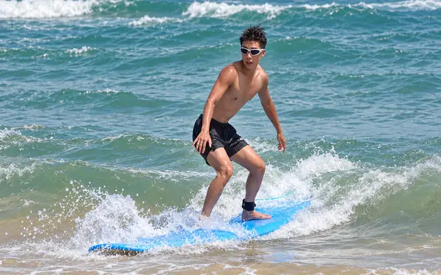 A guest riding a small wave on a surfboard